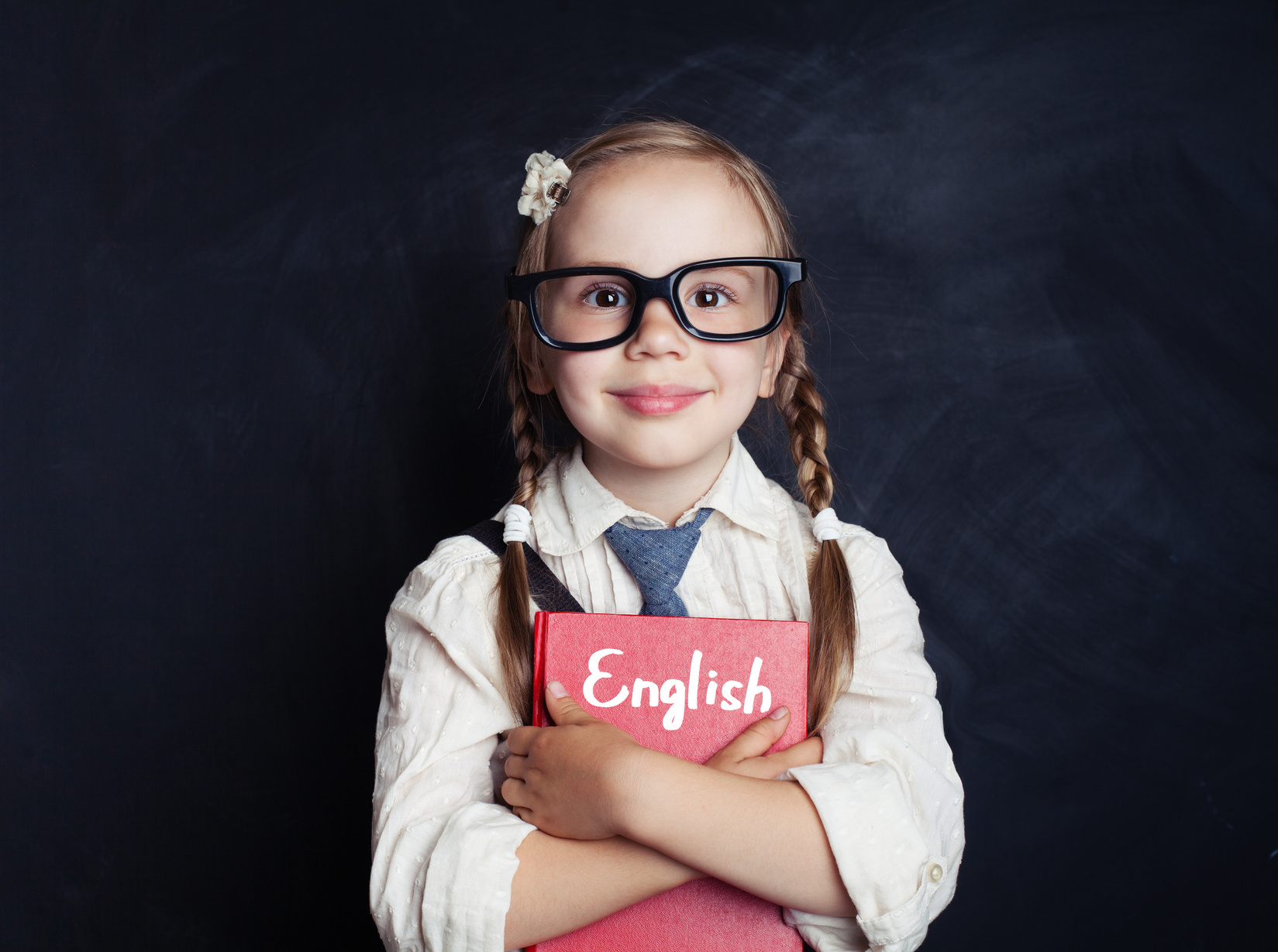 English concept with little schoolgirl student with pigtails and glasses. Smart kid learning english in language school